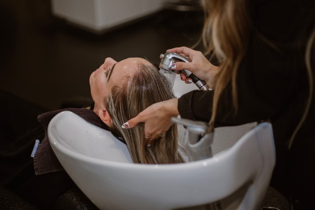 A woman gently brushes her hair in natural light, focusing on her scalp and healthy hair care routine.