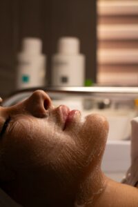 Person reclining during a facial while a skin-care professional applies a soothing mask.