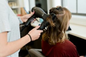 Person washing colored hair with lukewarm water while applying conditioner to the lengths.